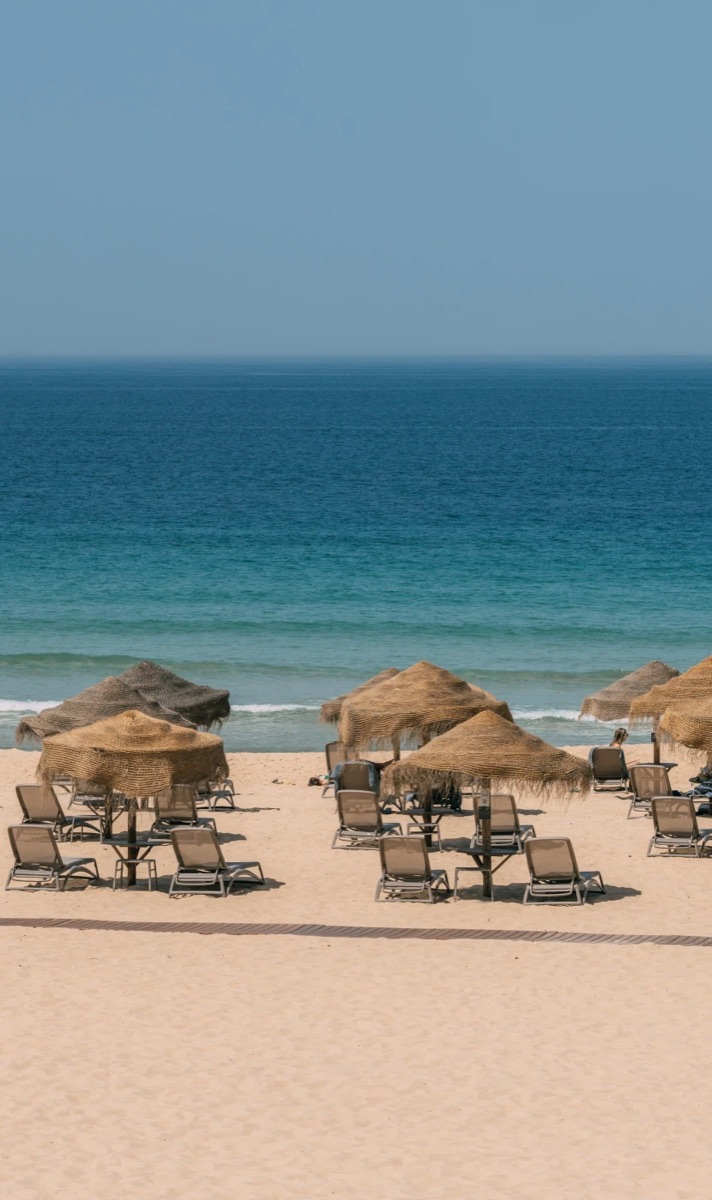 Thatched parasols on the pale sand of Comporta beach